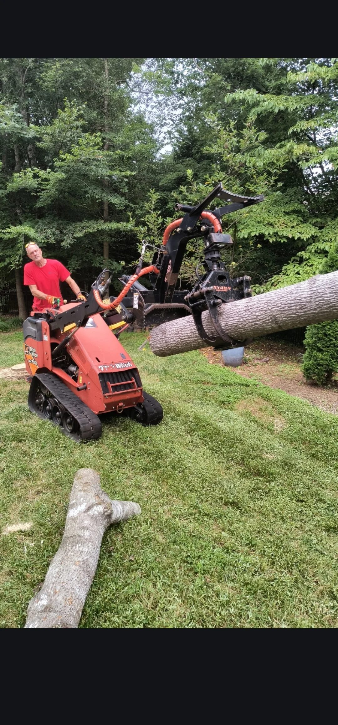 Tree service professional operating red tracked chipper and log processor on large felled tree